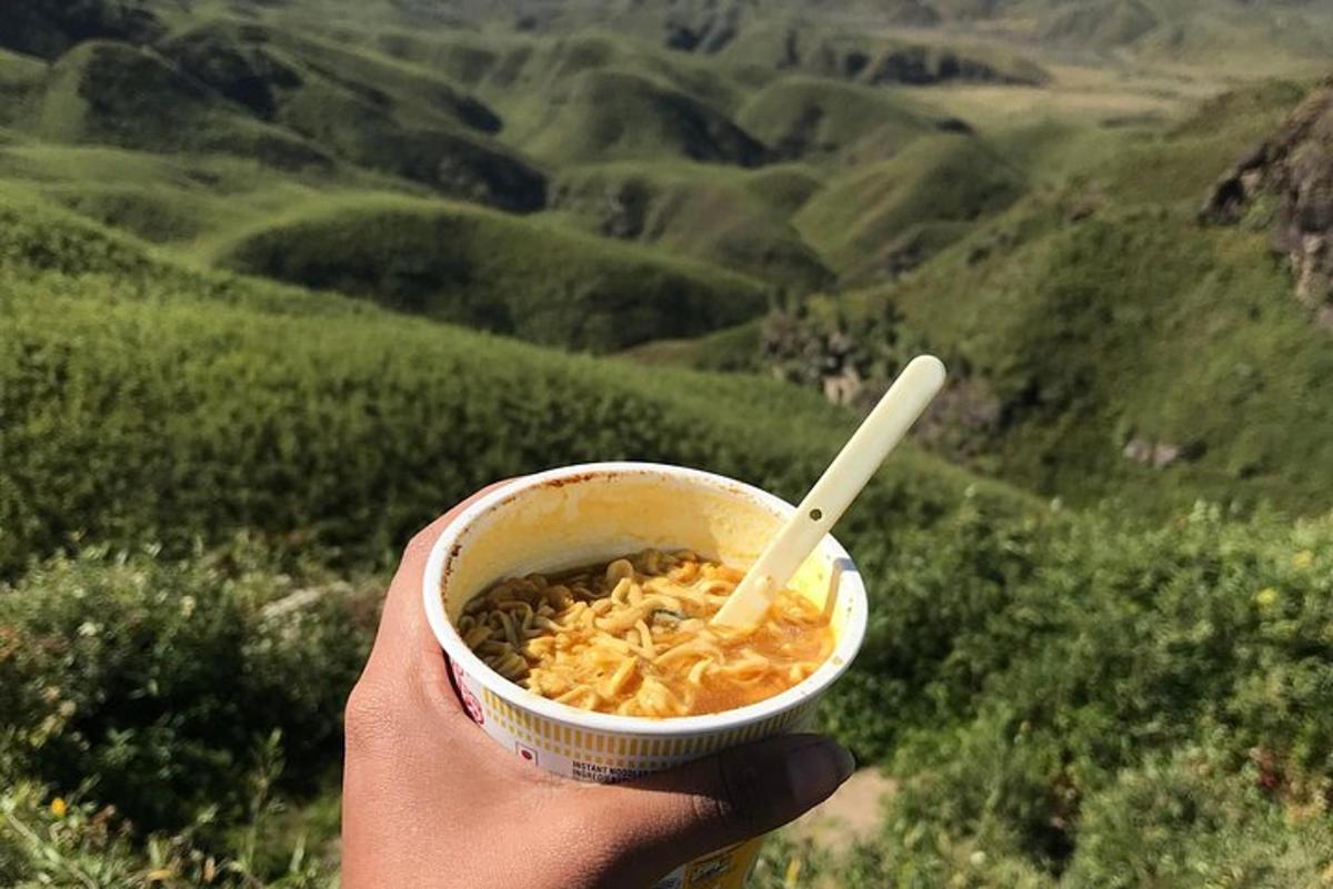 a person holding a bowl of food with a spoon