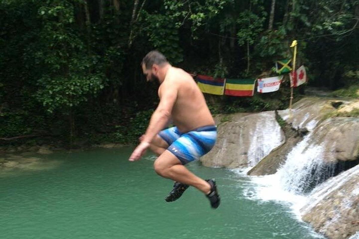um homem pulando de uma cachoeira em um corpo d'água