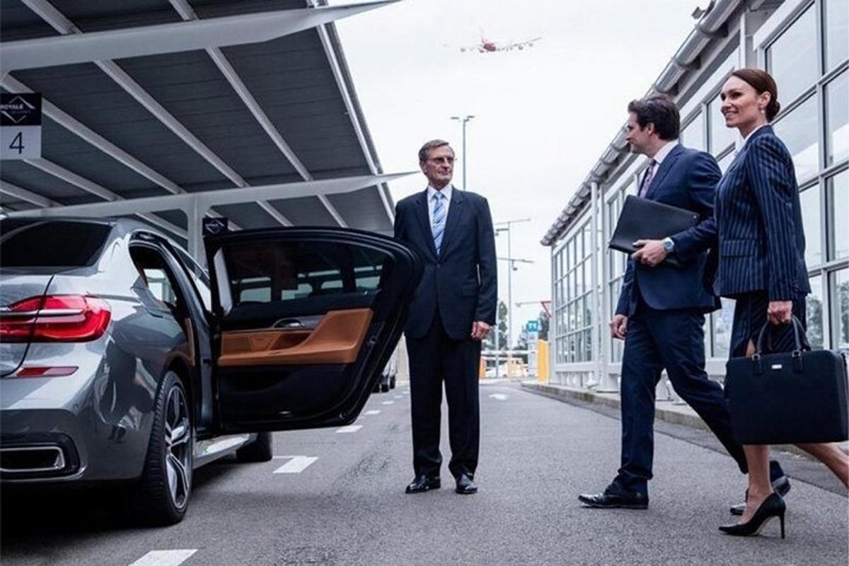 Trei bărbați în costume stau lângă o mașină