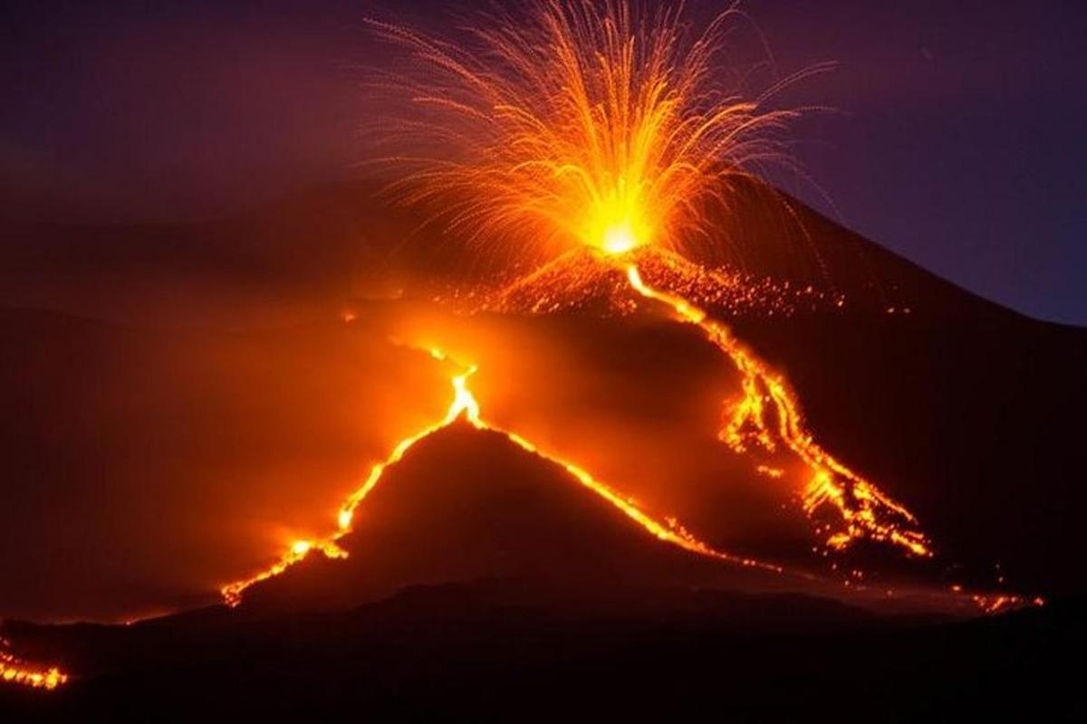 una montagna con un'eruzione di fuoco di notte