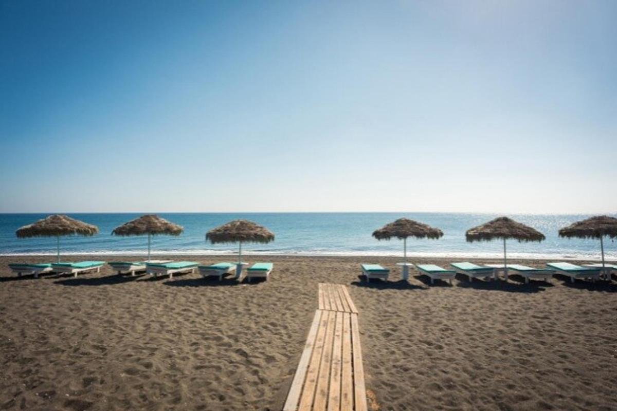 μια παραλία με ομπρέλες και ξαπλώστρες και τον ωκεανό