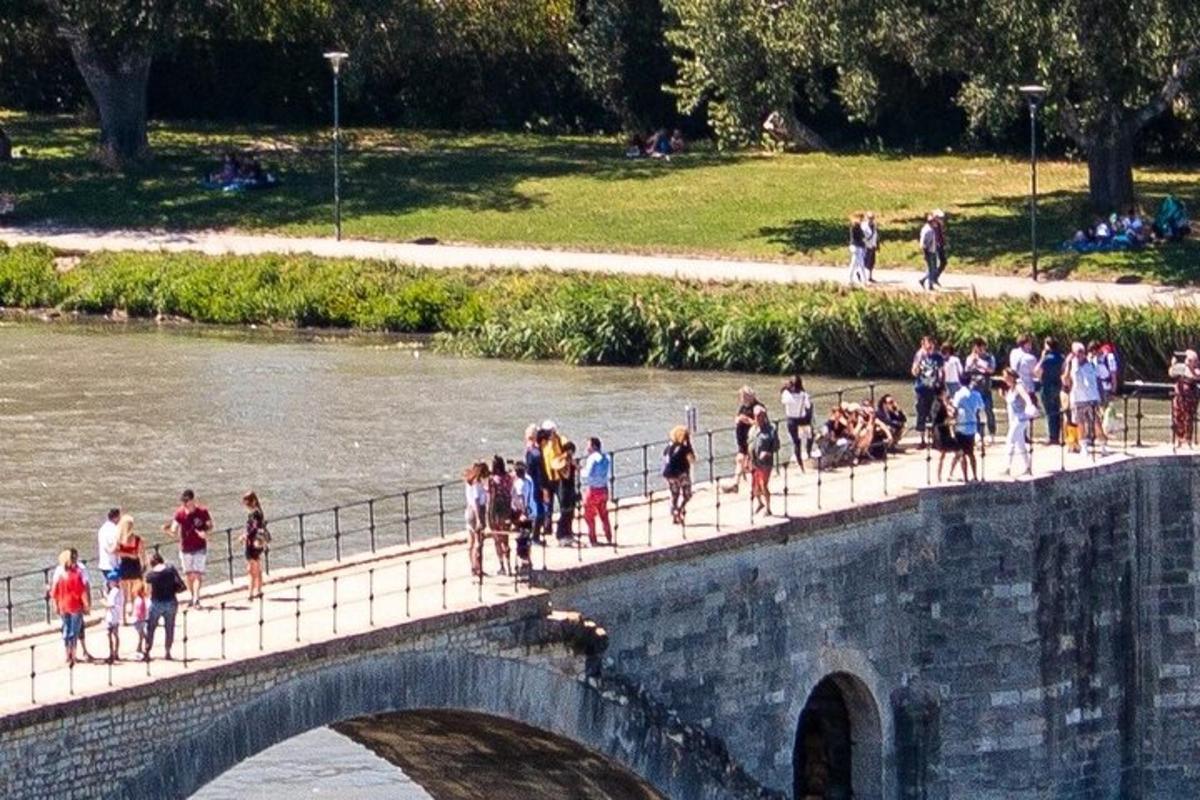 skupina lidí jdoucích po mostě přes řeku