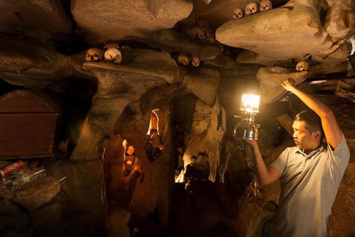 a man holding a light in a cave with animals on the ceiling