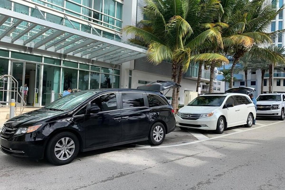 dois carros estacionados em frente a um prédio com palmeiras