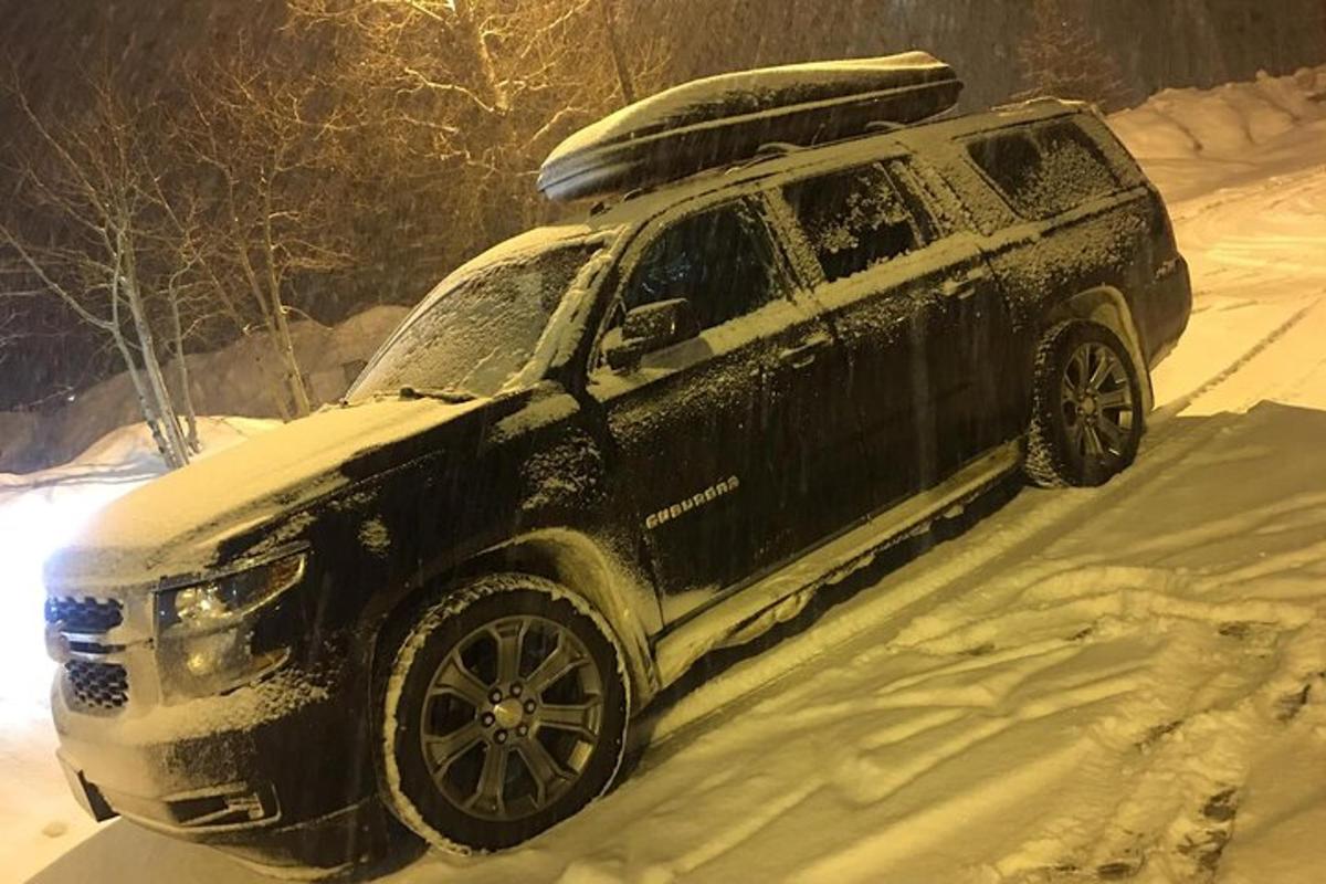 un SUV coperto di neve che percorre una strada innevata