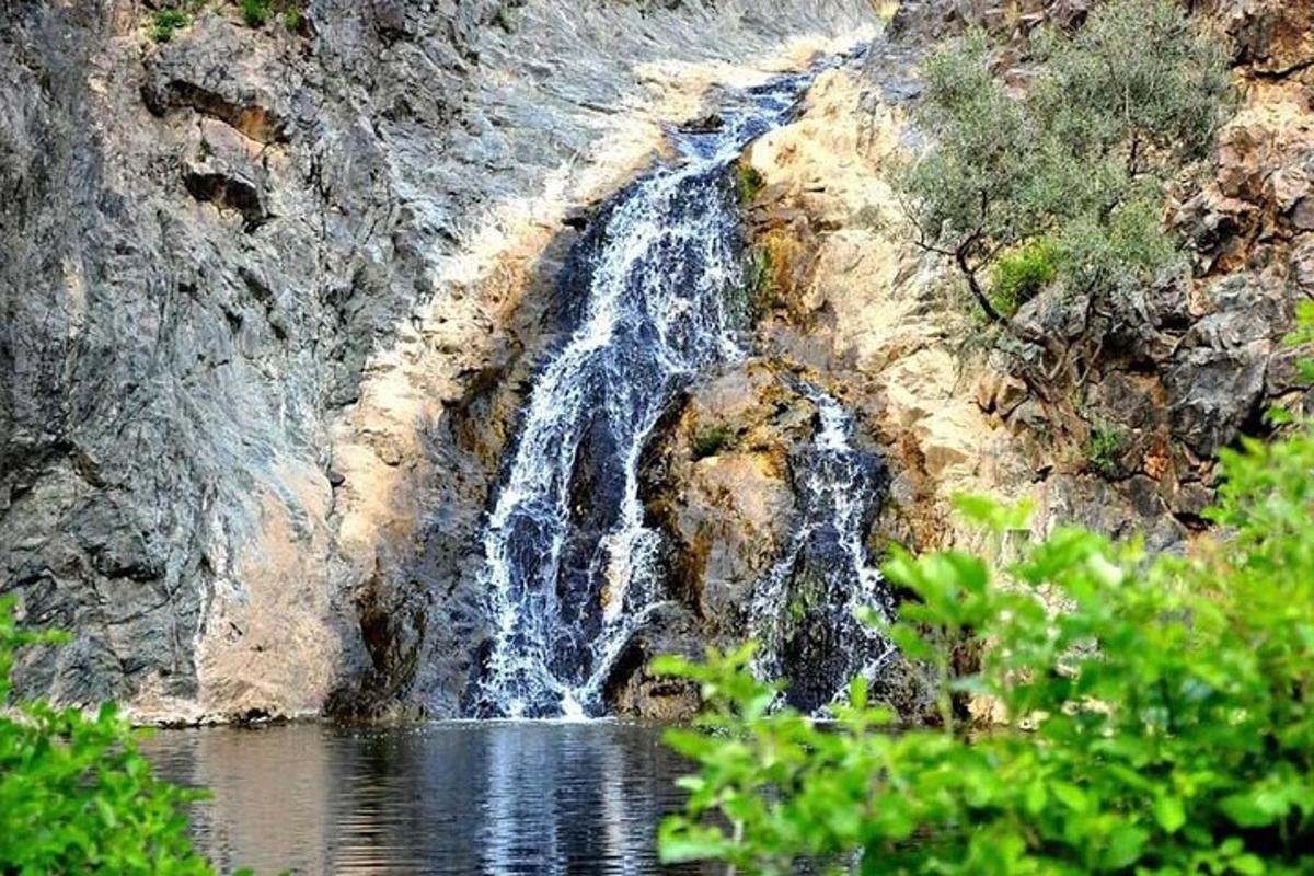 ένας καταρράκτης στην πλαγιά ενός βουνού δίπλα σε ένα υδάτινο σώμα