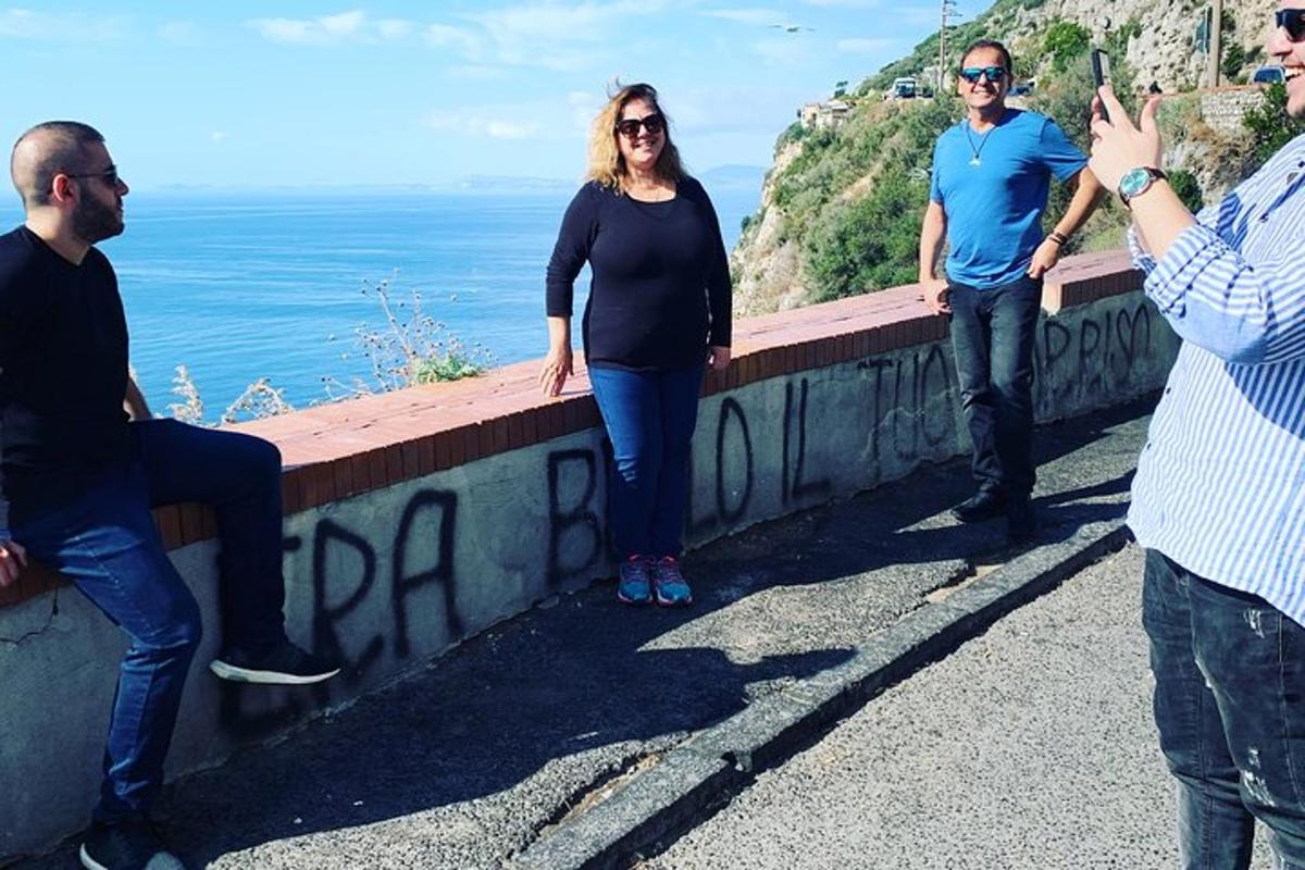 eine Gruppe von Menschen steht auf einer Mauer in der Nähe des Ozeans