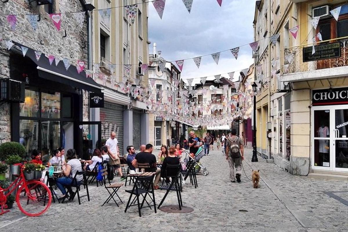 um grupo de pessoas caminhando por uma rua com mesas e cadeiras