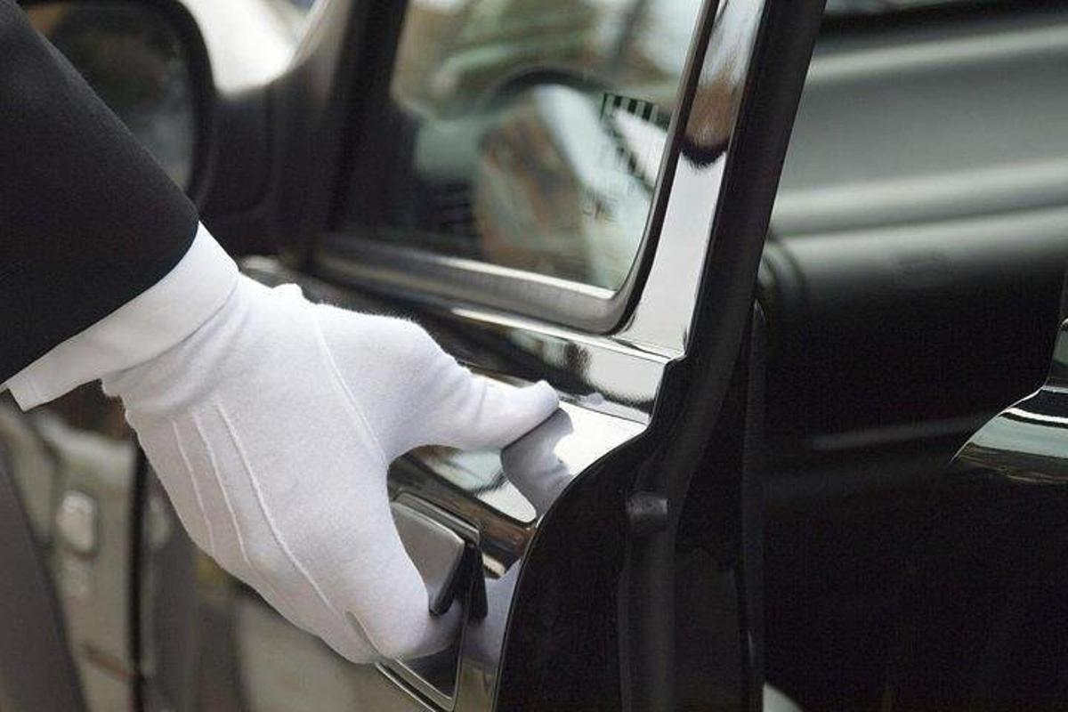 a person in white gloves unlocking a car door