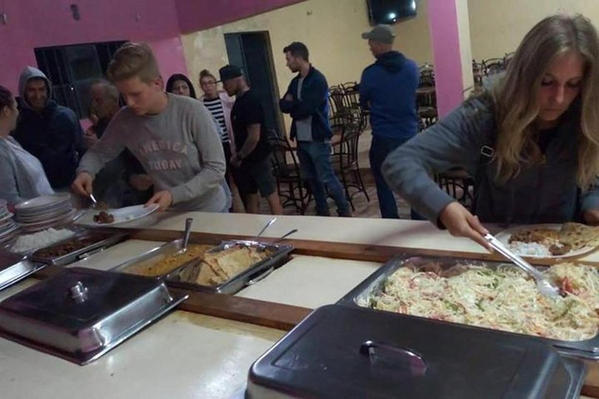 un gruppo di persone in piedi attorno a un buffet di pizze