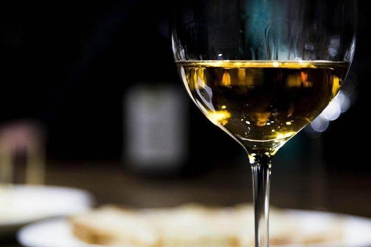 a glass of white wine sitting on a table