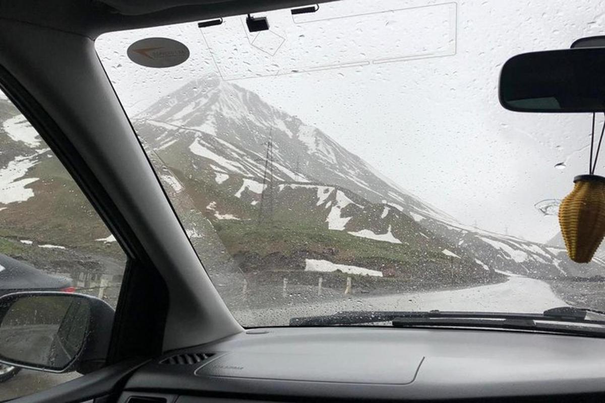 Blick auf einen schneebedeckten Berg von einer Autowindschutzscheibe aus