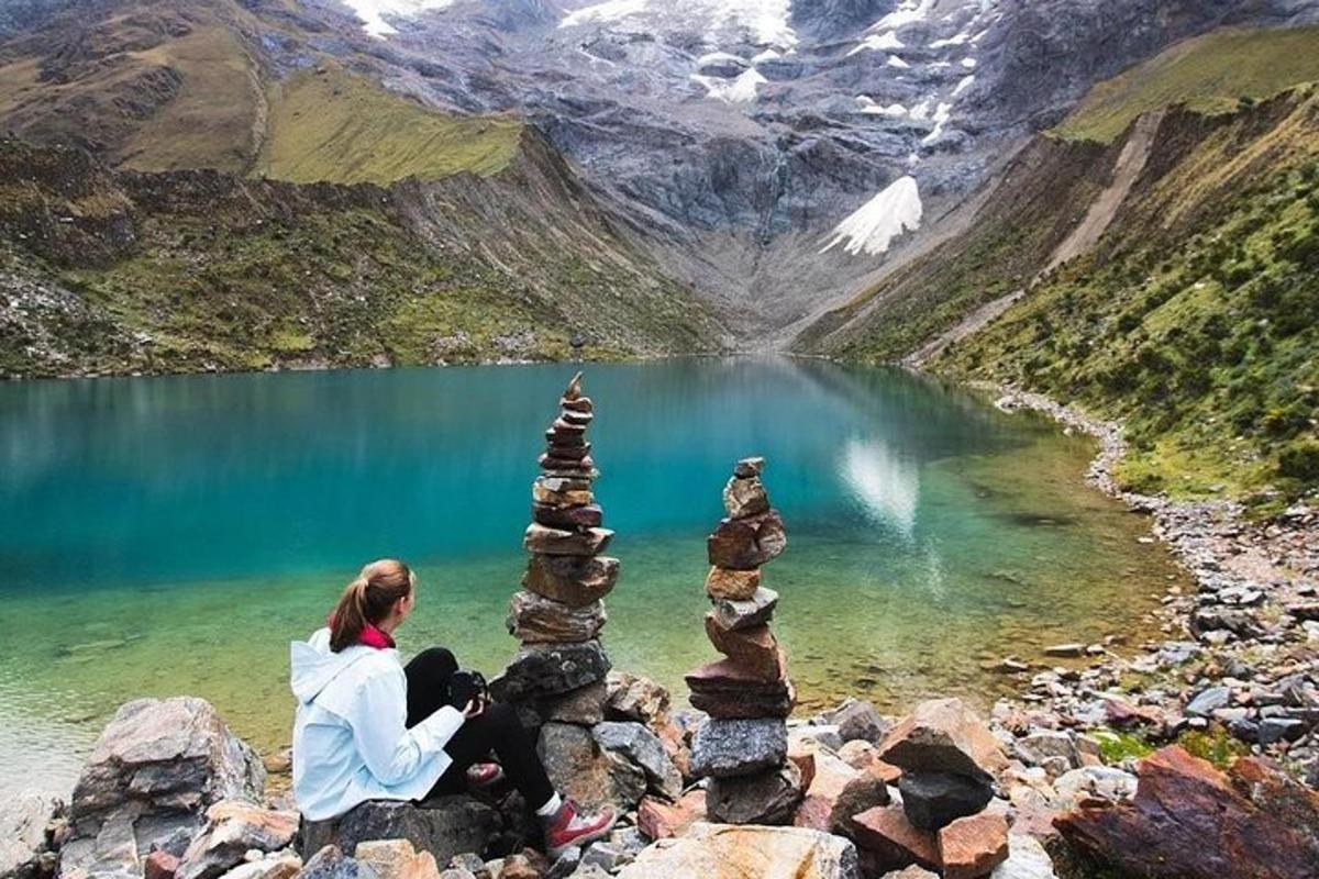 seorang wanita duduk di atas timbunan batu di hadapan sebuah tasik