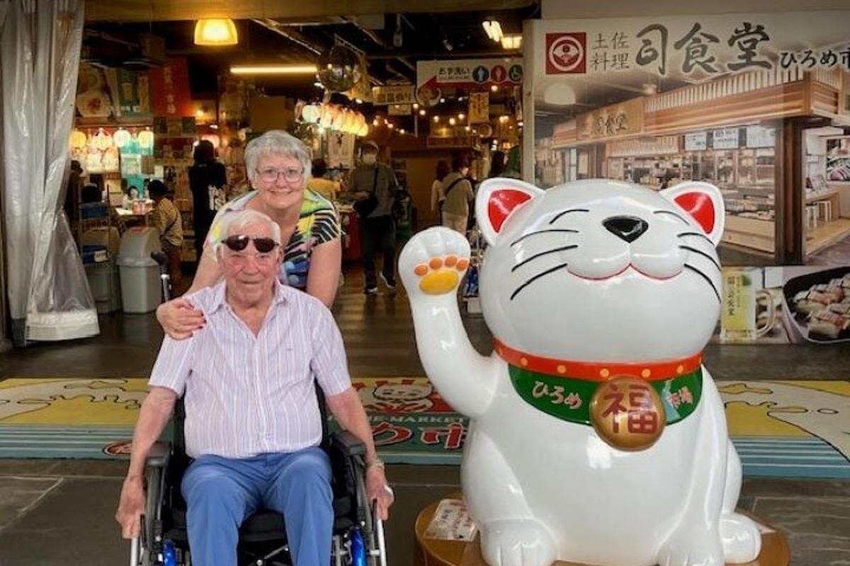 an older man in a wheelchair next to a giant stuffed cat