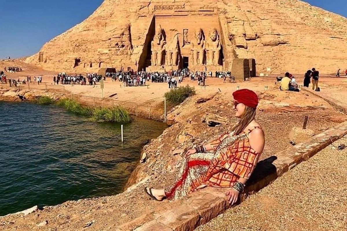 una donna seduta su un muro di fronte a una piramide