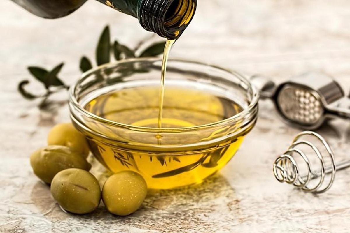 una ciotola di vetro piena di olio d'oliva accanto alle olive verdi