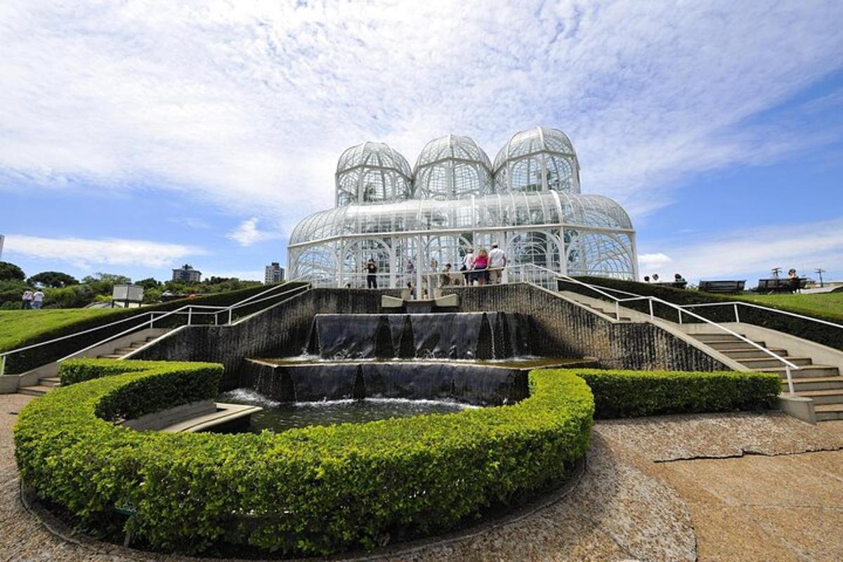 a glass house with a fountain in front of it