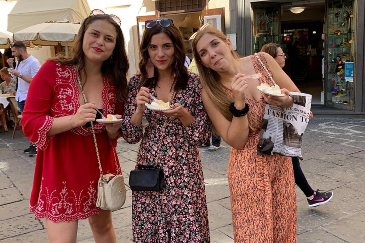 tre donne stanno mangiando cibo in una strada cittadina