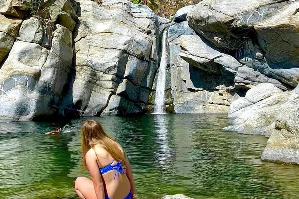una donna in bikini in piedi davanti a una cascata