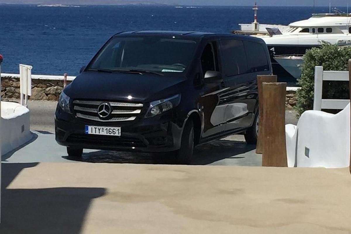 en svart varebil parkert på en parkeringsplass nær vannet