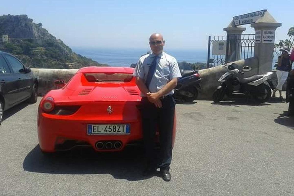um homem está parado ao lado de um carro vermelho