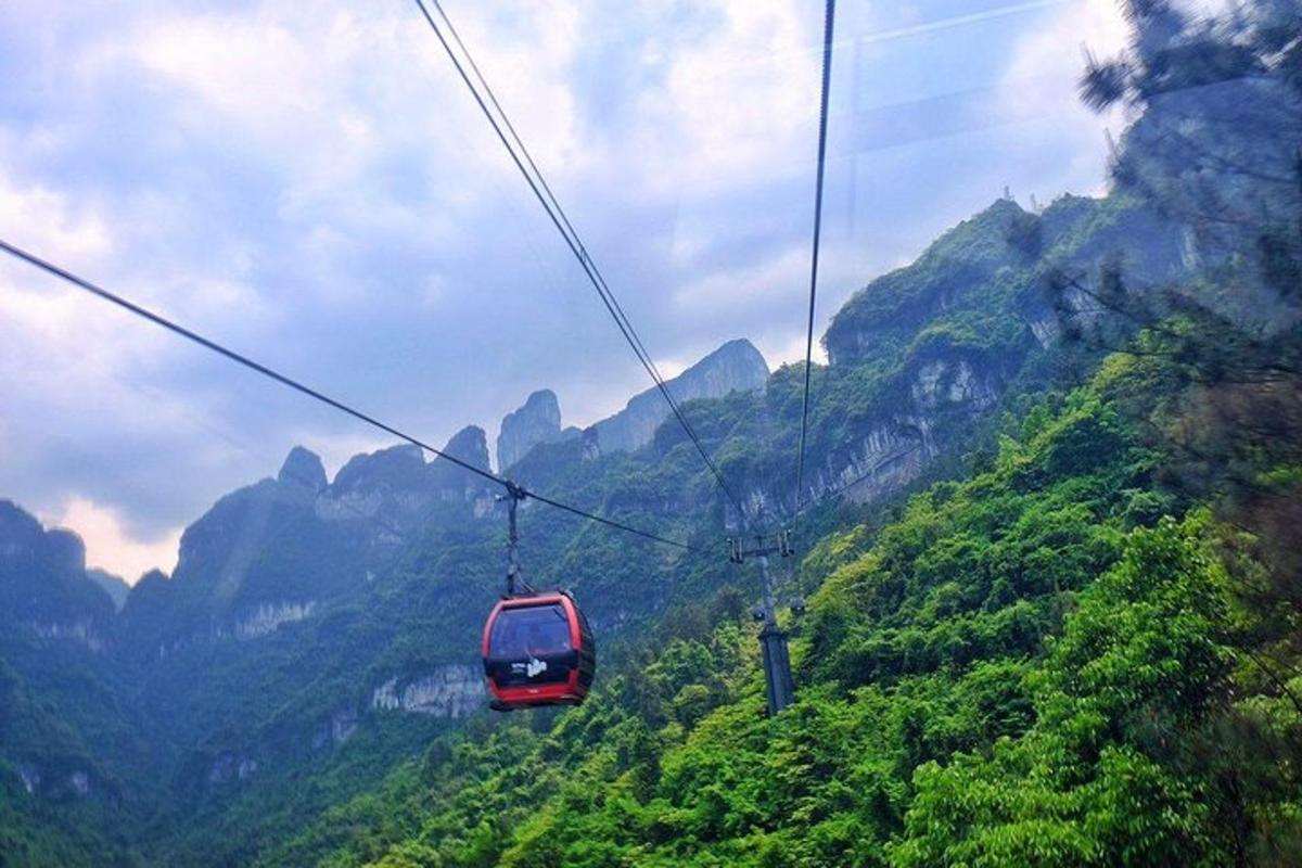a red cable car flying through the mountains