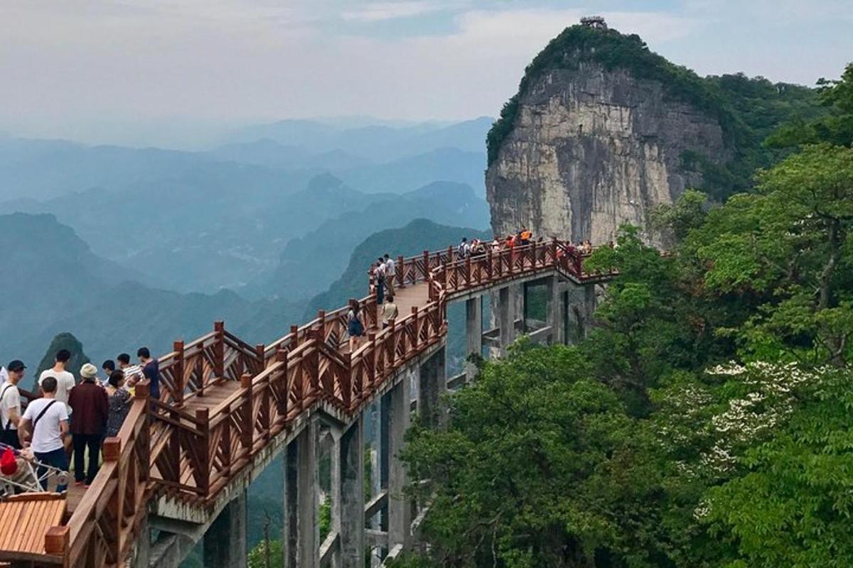 a group of people standing on a bridge in the mountains