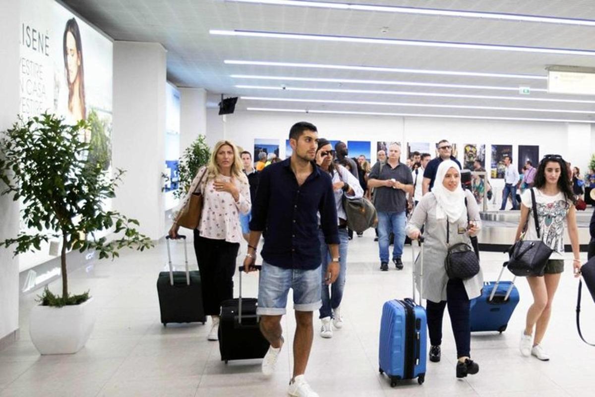 skupina ľudí prechádzajúcich sa po letisku s batožinou
