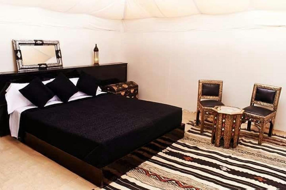 una camera da letto con un letto, uno specchio e delle sedie