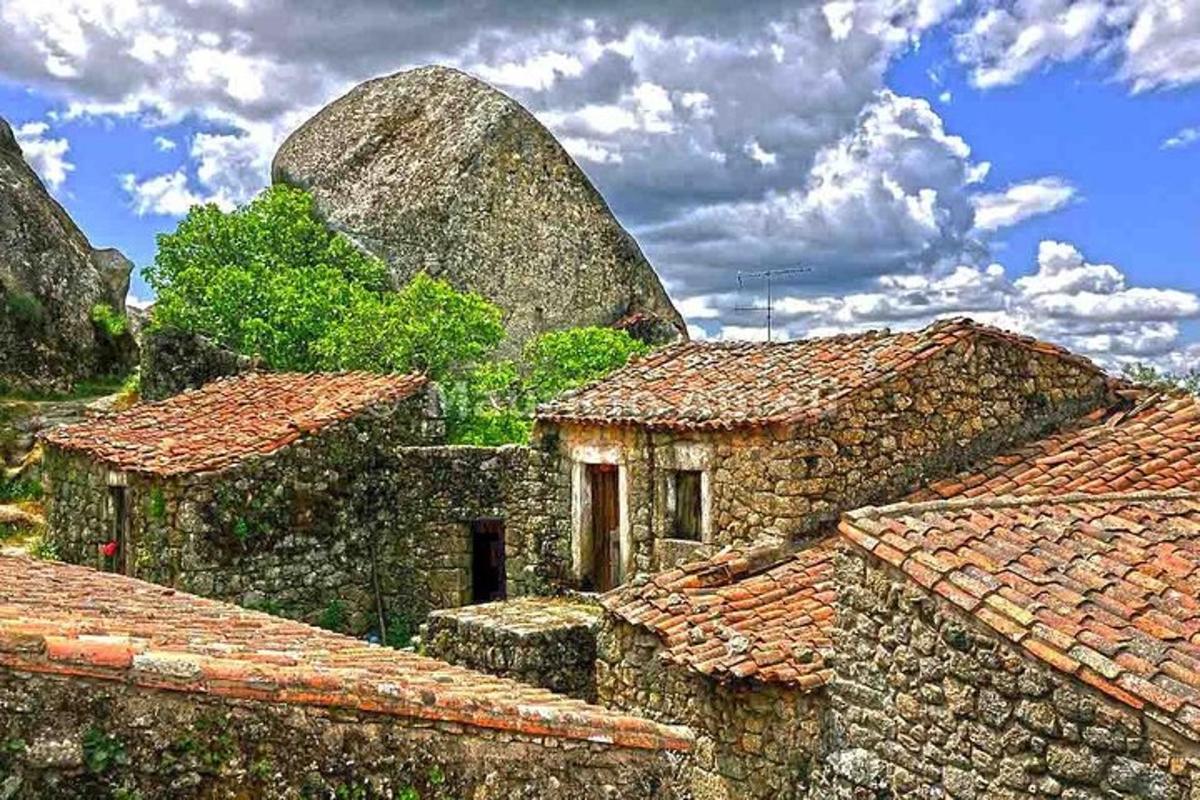 un vecchio edificio in pietra con tetti di tegole rosse e una montagna