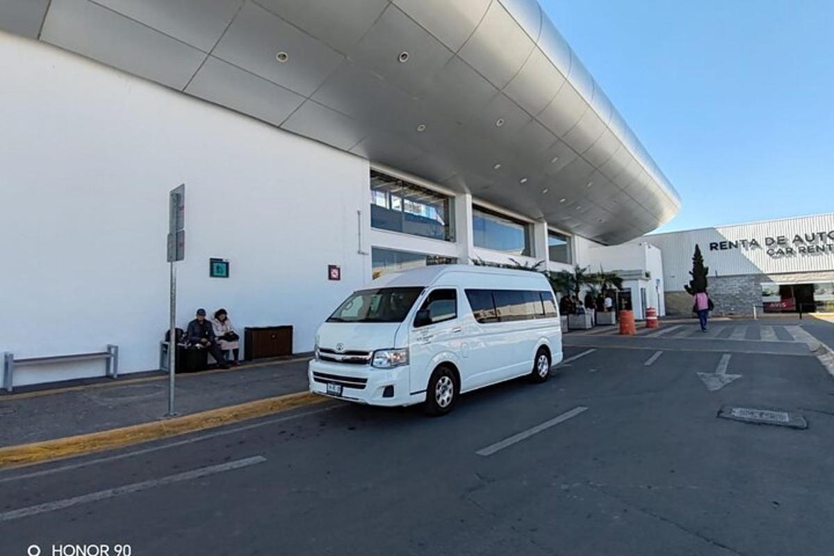Una camioneta blanca estacionada en un estacionamiento frente a un edificio.
