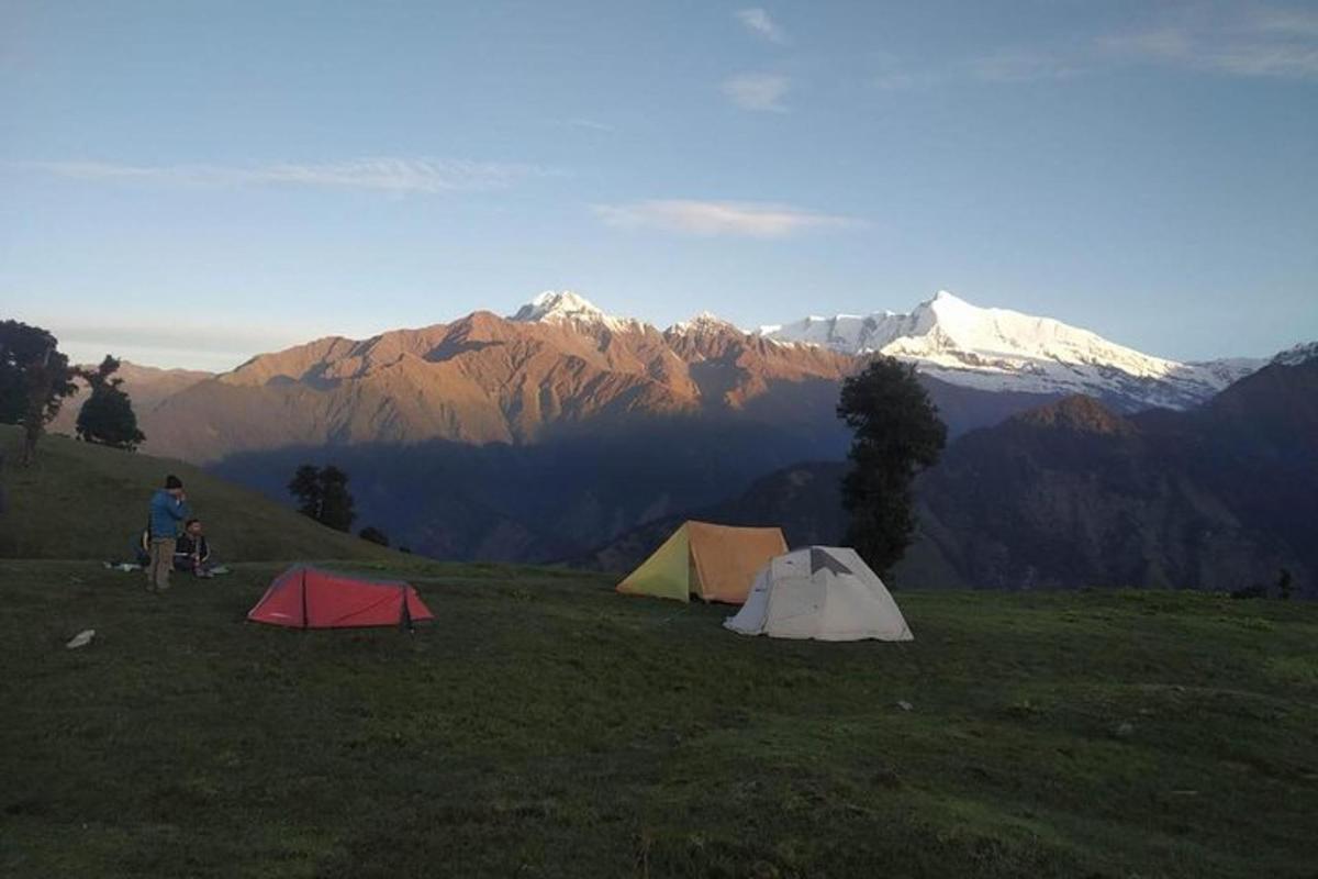 two tents on a hill with mountains in the background