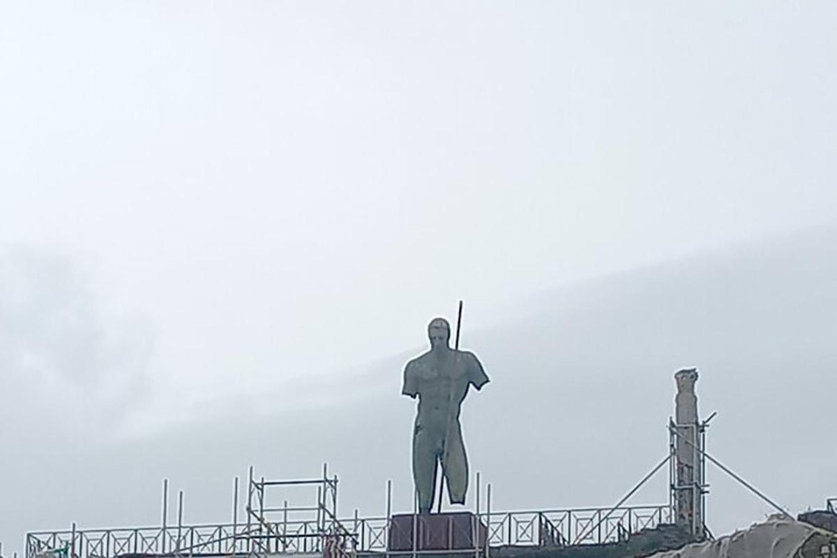 uma estátua de um homem em pé no topo de um edifício