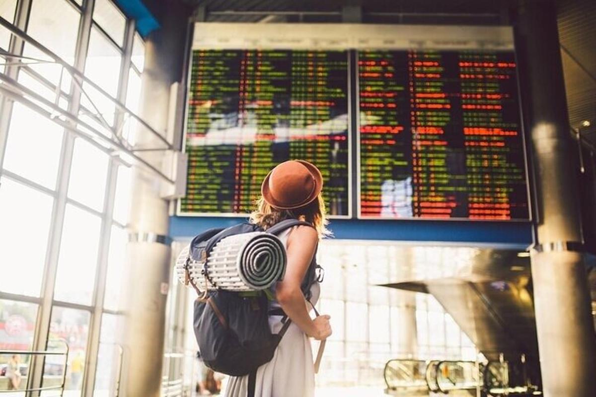 seorang wanita dengan beg galas melihat jadual penerbangan