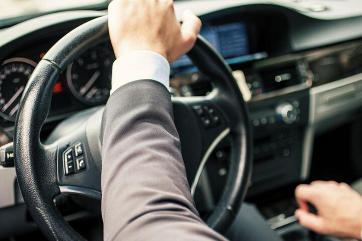seseorang memandu kereta dengan tangan mereka pada stereng
