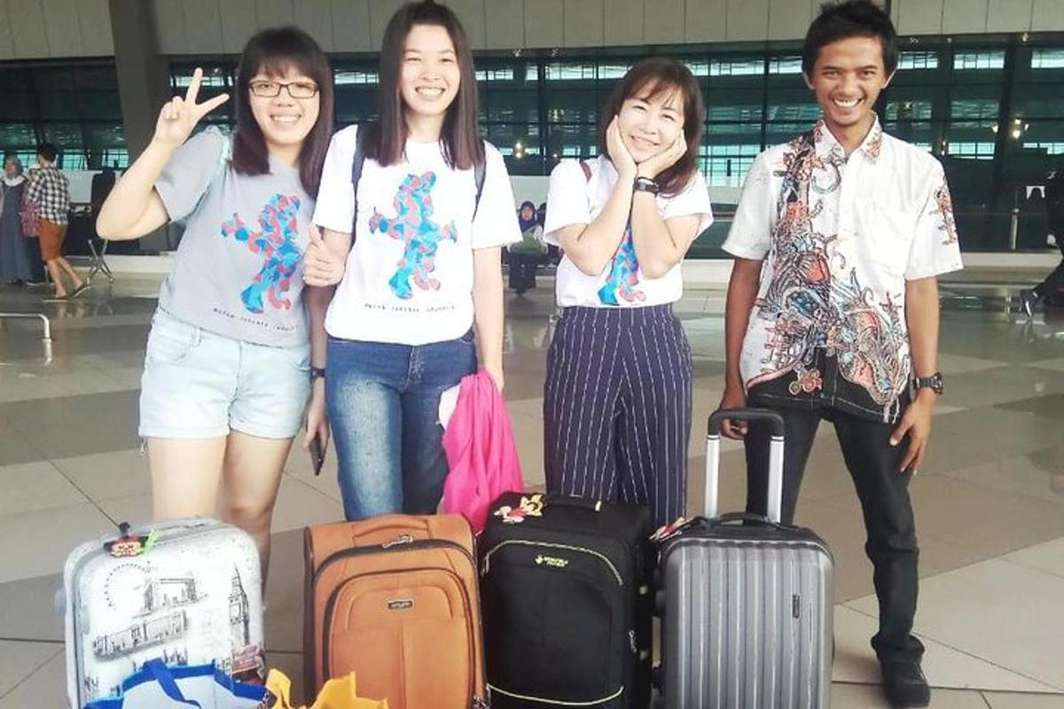 กลุ่มคนกำลังยืนอยู่ที่สนามบินพร้อมสัมภาระ
