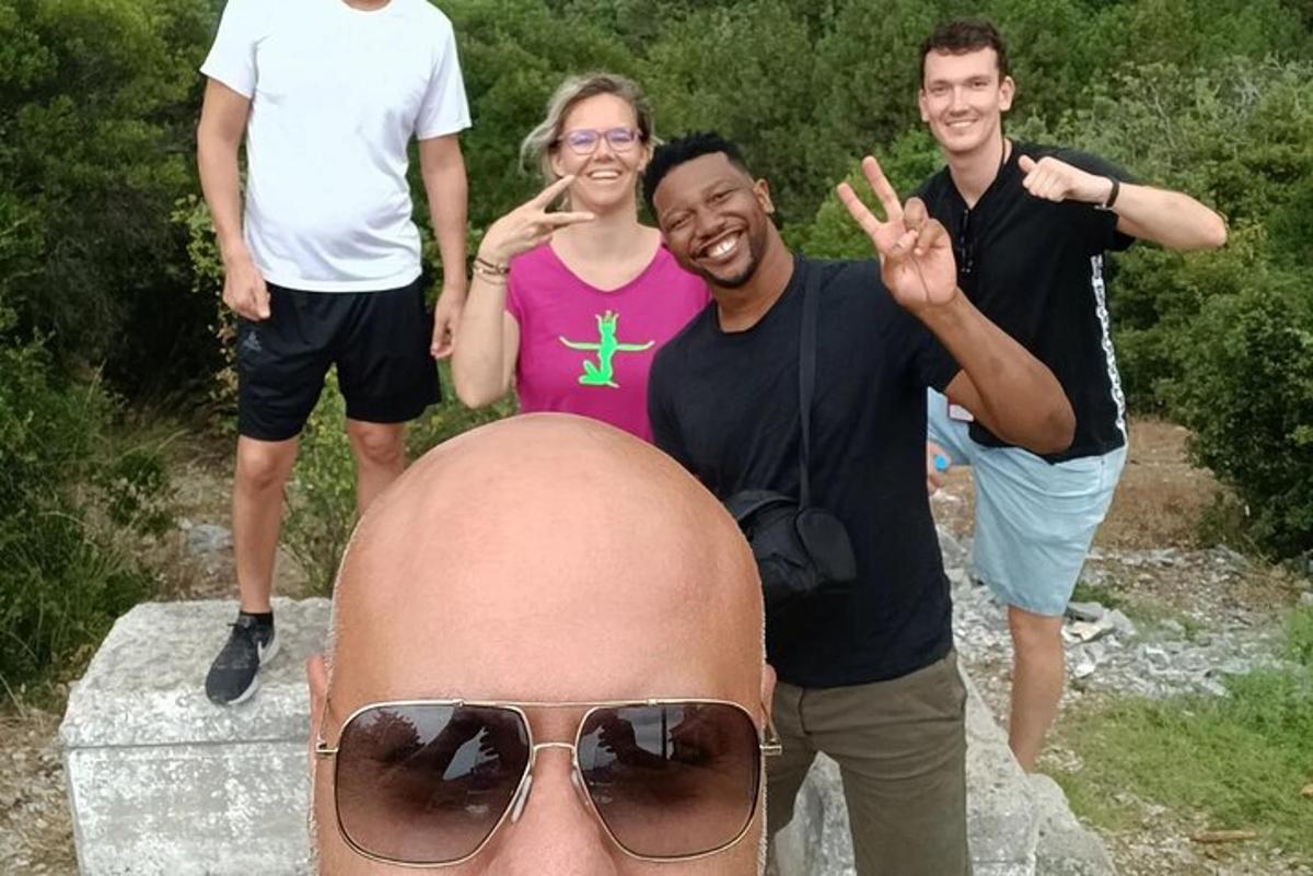 un gruppo di persone in piedi attorno a un uomo che indossa occhiali da sole