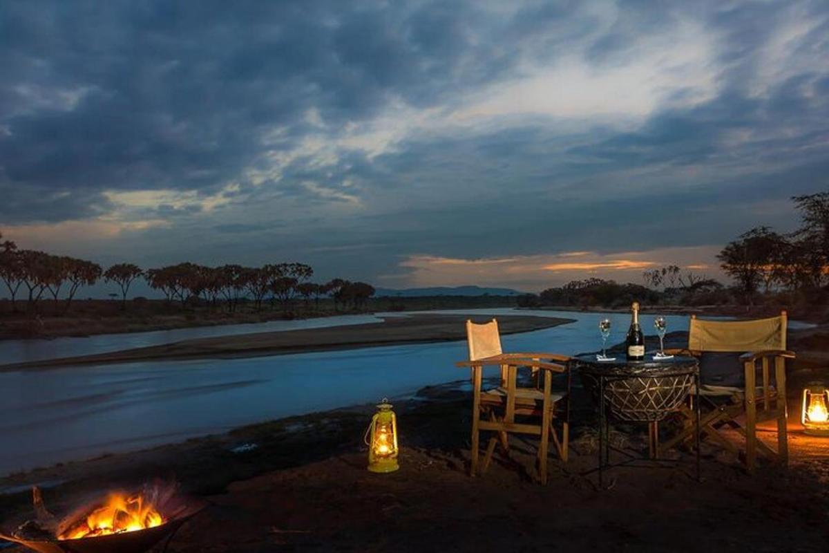 a table and chairs next to a river with afire