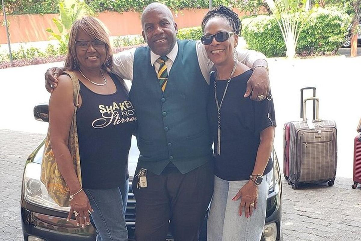 um homem e duas mulheres parados ao lado de um carro