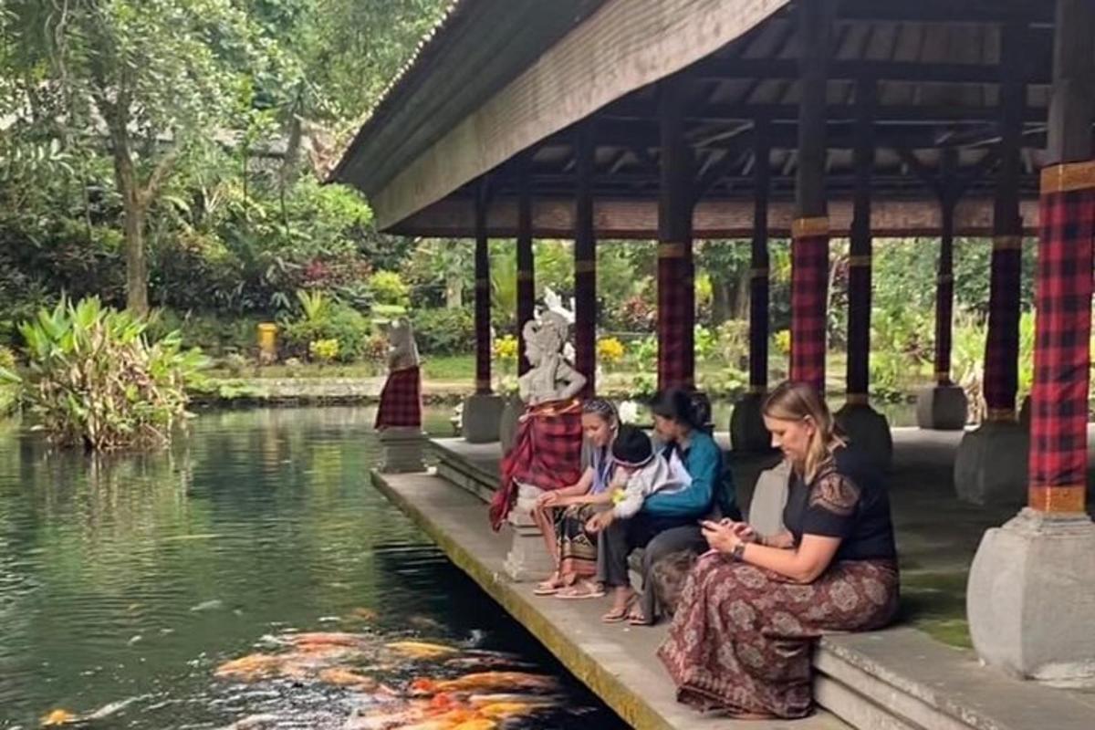 isang grupo ng mga tao na nakaupo sa ilalim ng gazebo malapit sa isang lawa
