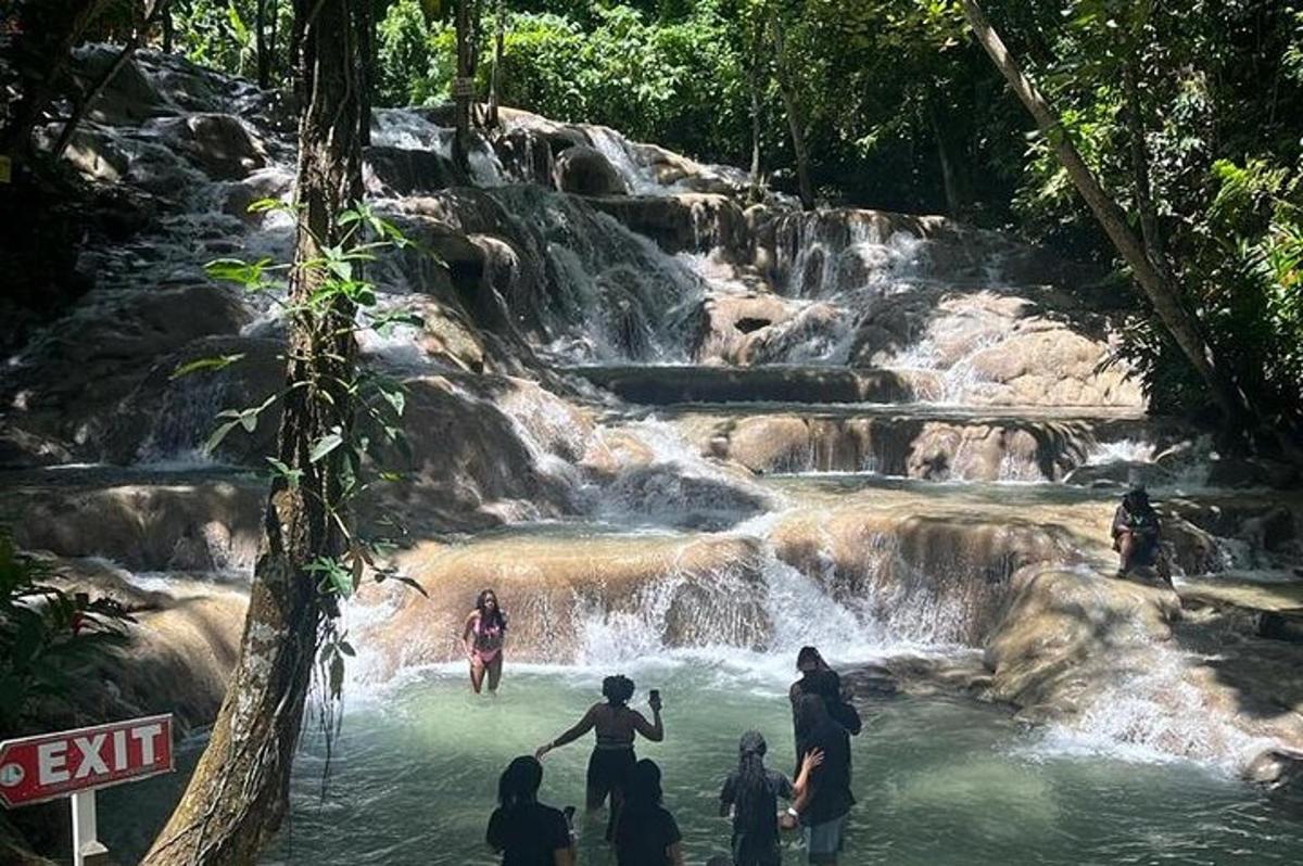 Un grupo de personas de pie en el agua cerca de una cascada.