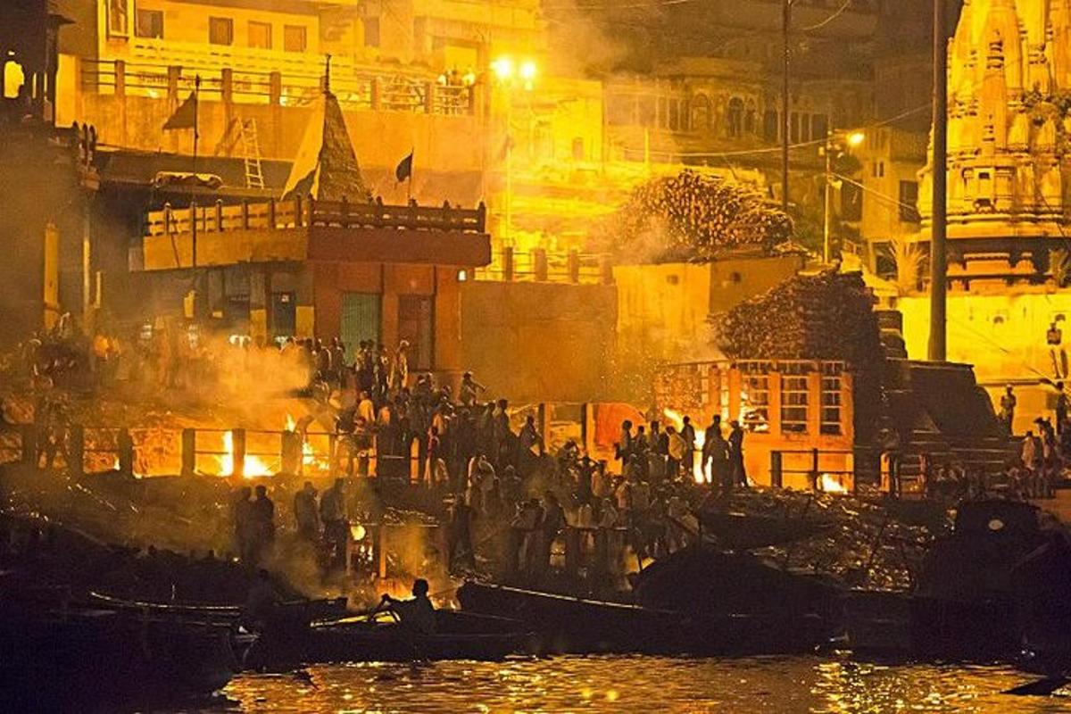 hópur fólks stendur í bátum á vatninu að nóttu til