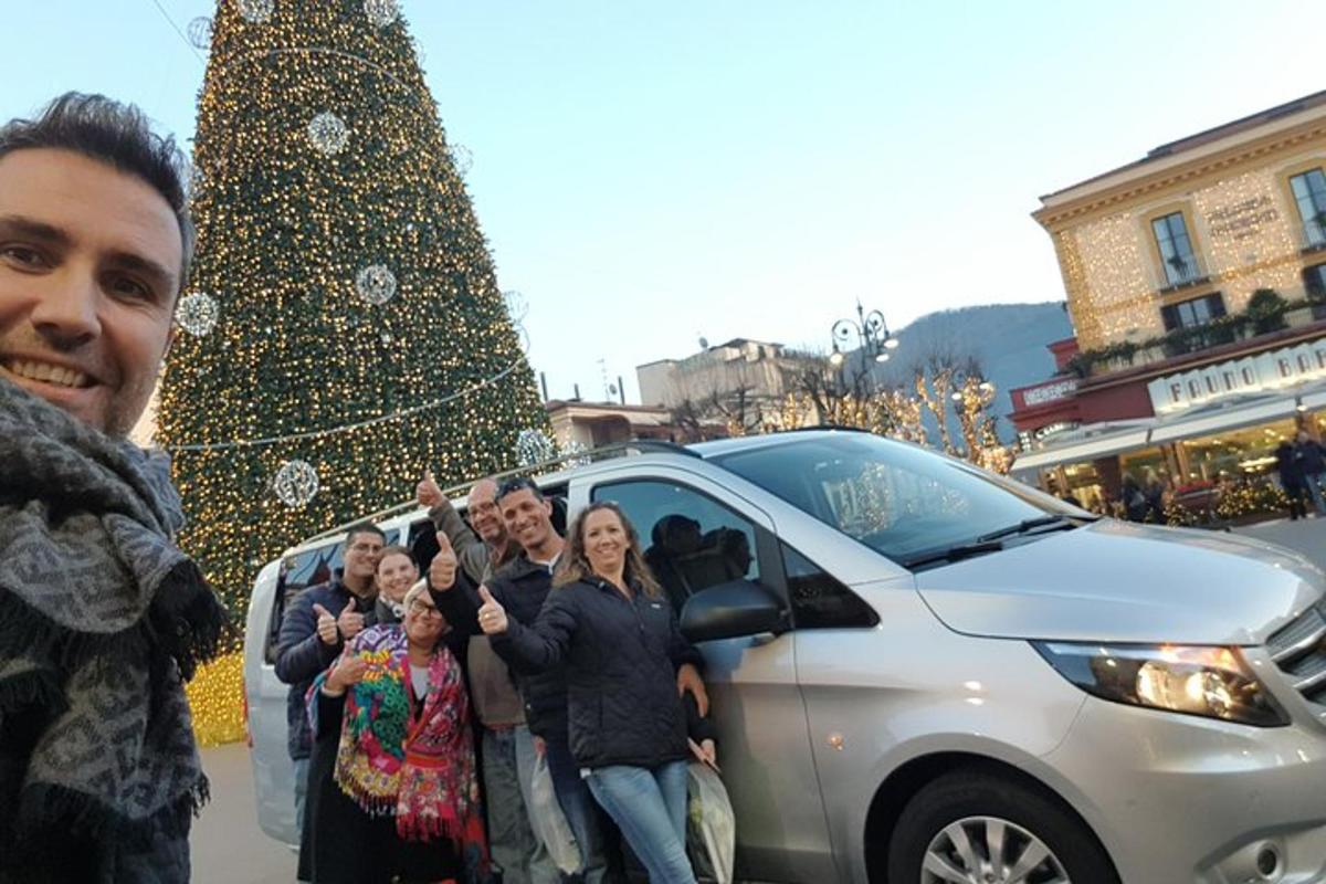 Μια ομάδα ανθρώπων που στέκονται δίπλα σε ένα αυτοκίνητο δίπλα σε ένα χριστουγεννιάτικο δέντρο