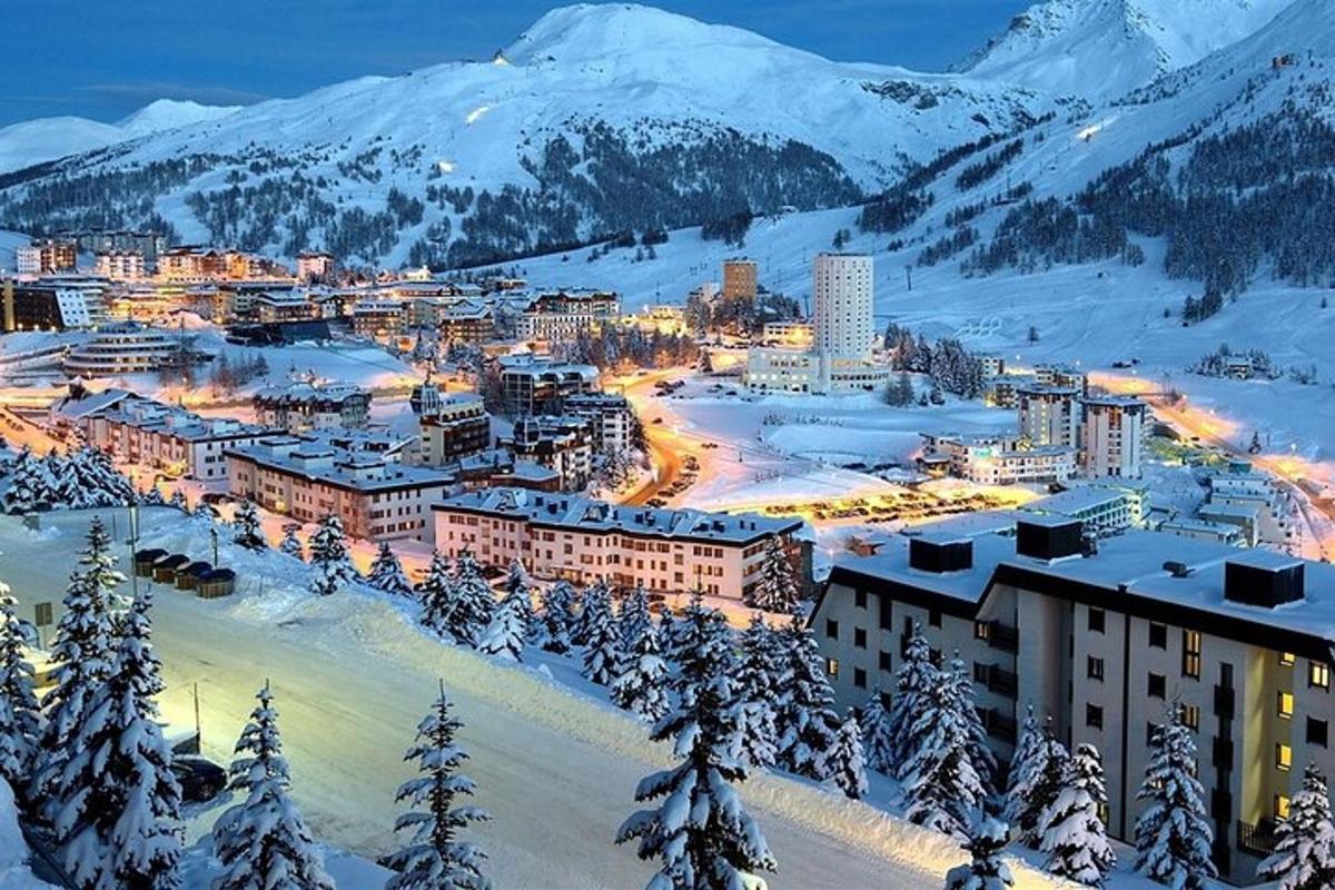 a city in the snow with snow covered mountains