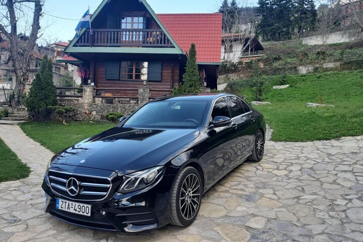 Černé auto Mercedes Benz zaparkované před domem