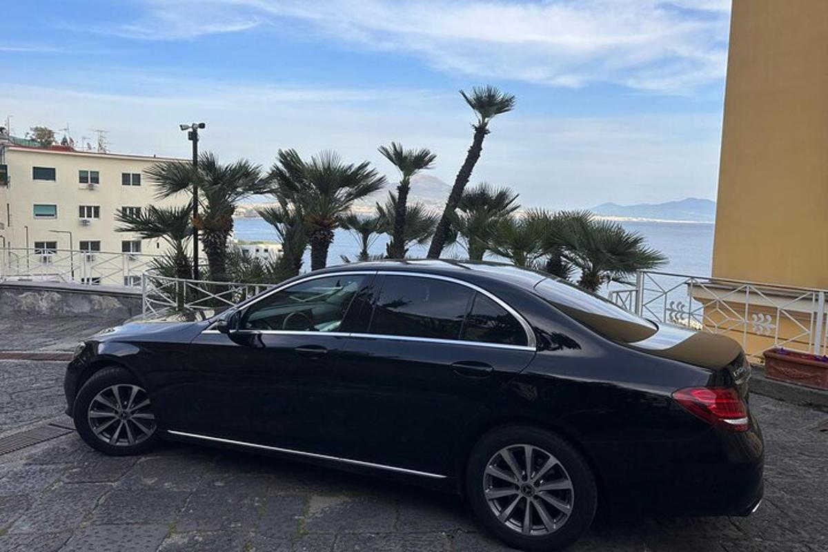 a black car parked on a street near the ocean