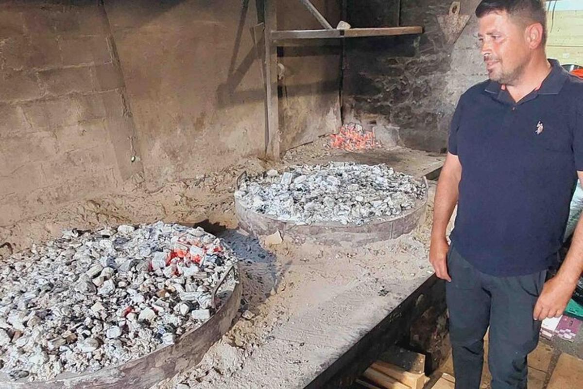 en mann som står foran en grill med to panner