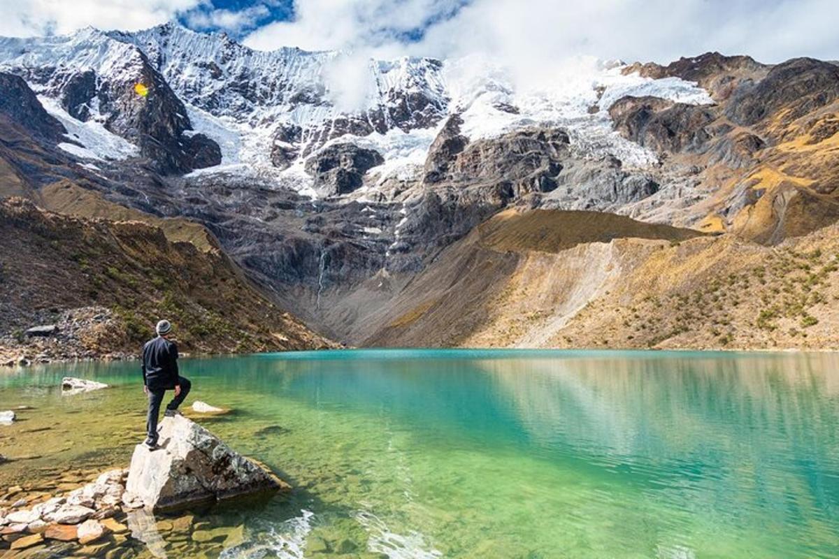 un uomo in piedi su una roccia vicino a un lago di montagna