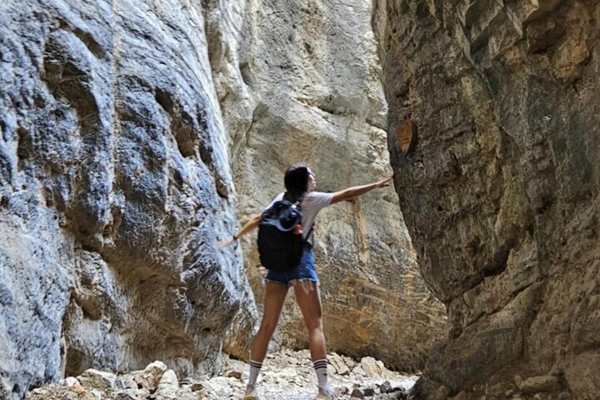 una donna in piedi in un canyon con le braccia tese