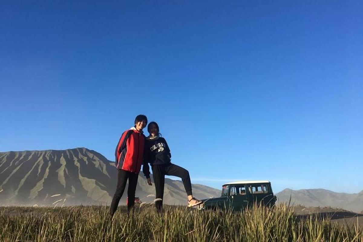 a man and a woman standing in a field with a truck
